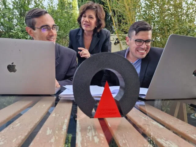 Carlos y Pedro sentados con su portátil y Paola de pie en medio interactuando